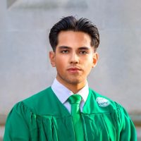 Mathew Hernandez wearing a green MSU graduation robe.